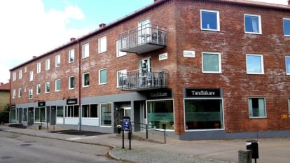 En röd, sliten tegelfasad med en tandläkarmottagning på bottenvåningen.