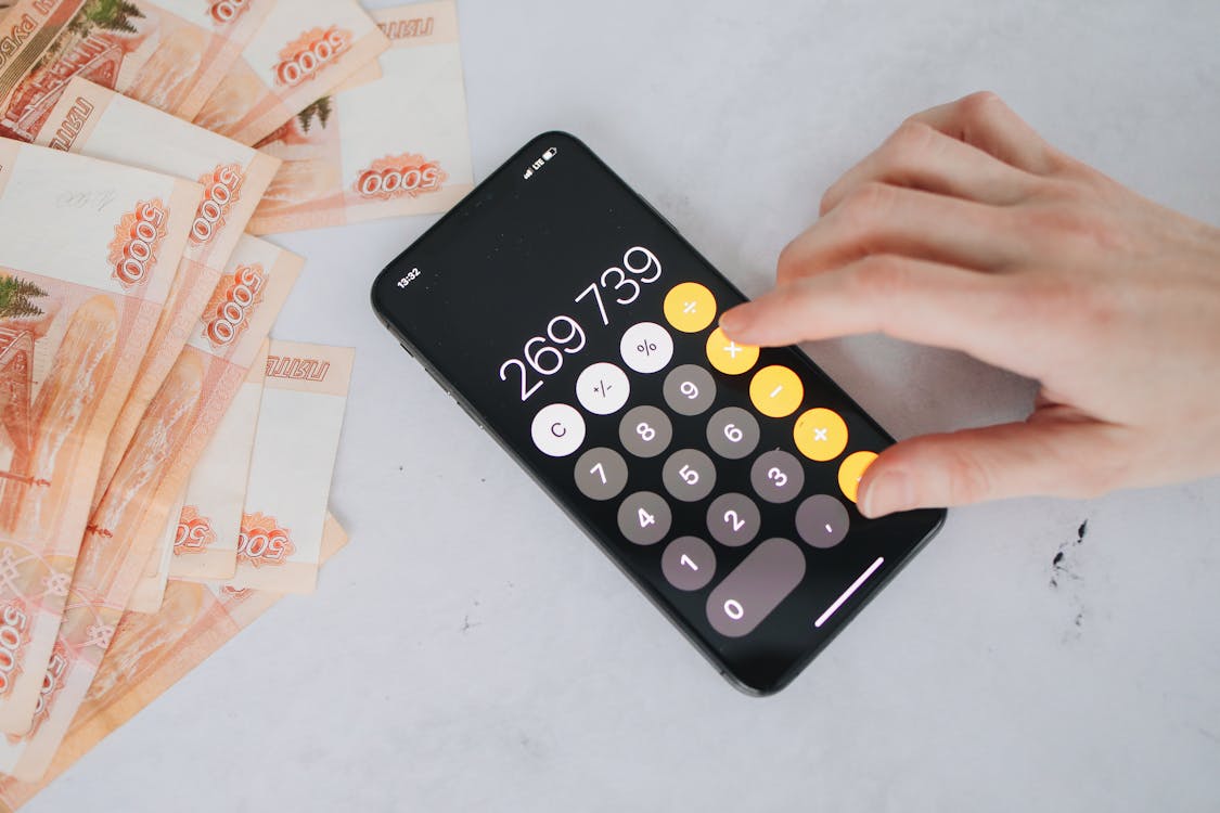 Free Person using smartphone calculator with Russian rubles on a table, representing financial planning. Stock Photo