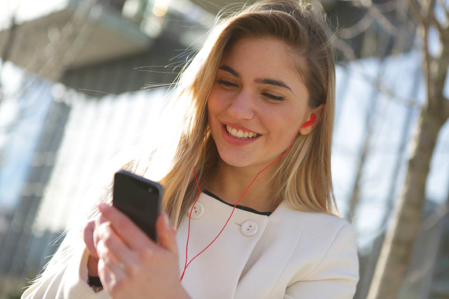 Imagen de una chica mirando su celular y escuchando música