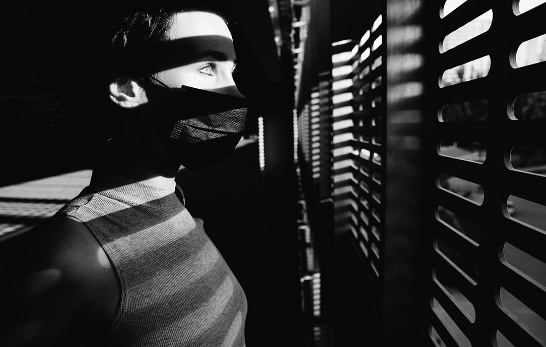 Lady wearing a face mask looking through shutter