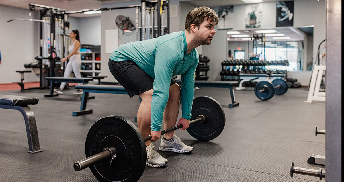 An instructor sets up to perform a deadlift in the gym.