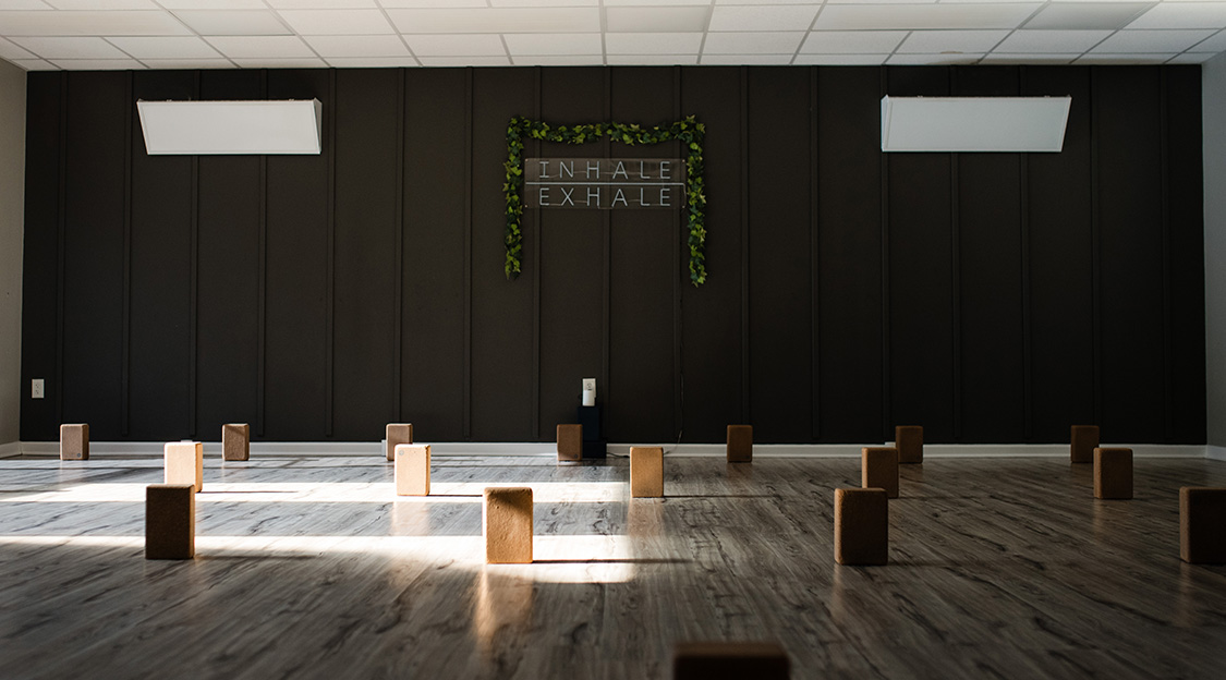 A wall in the Advanced Training studio has a sign that reads 'Inhale / Exhale'