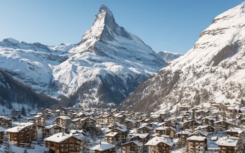 A panoramic view of Zermatt with the iconic Matterhorn mountain in the background, snow-covered slopes, and a charming alpine village.