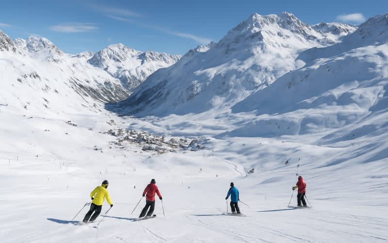 A panoramic view of the Val d'Isère ski resort, showcasing snow-covered mountains and skiers descending the slopes.