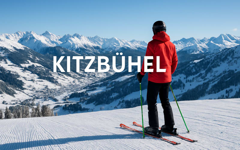 A panoramic view of Kitzbühel ski resort with snow-covered mountains and a skier in the foreground.