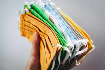 A hand holding a stack of face masks