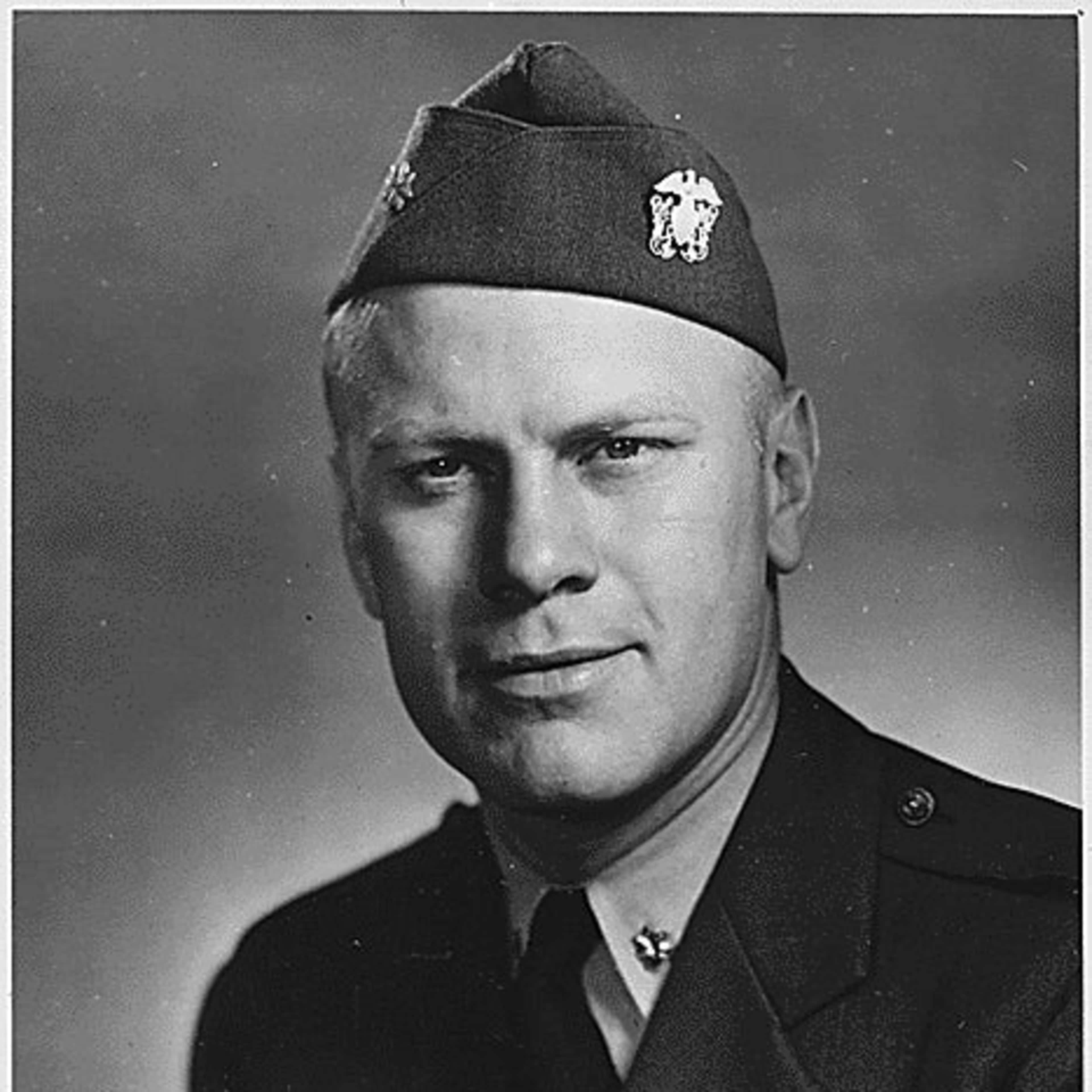 A black and white portrait photograph of a man wearing a military uniform with a cap and insignia, against a plain background.