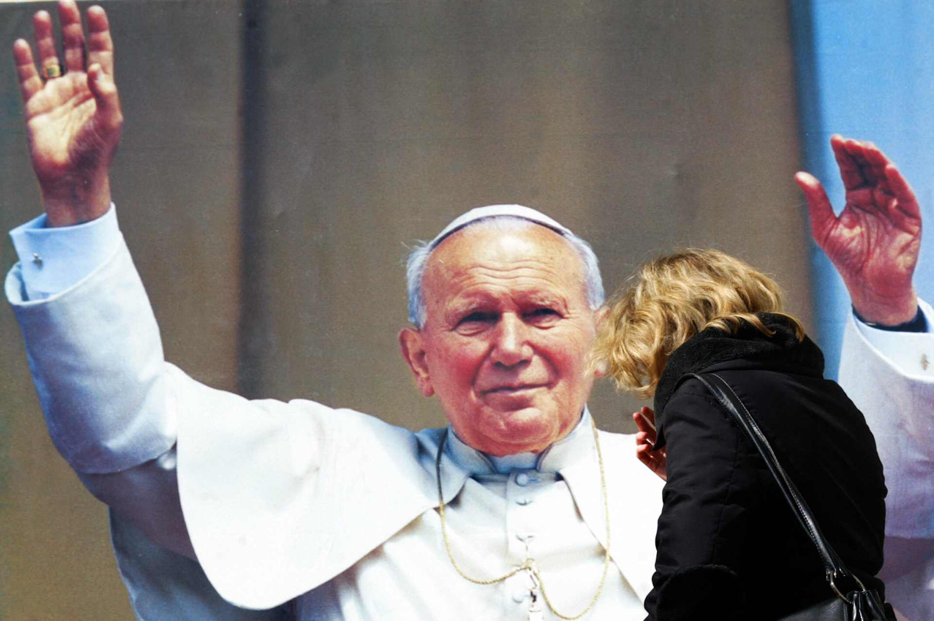 A Catholic prays in front of portrait of