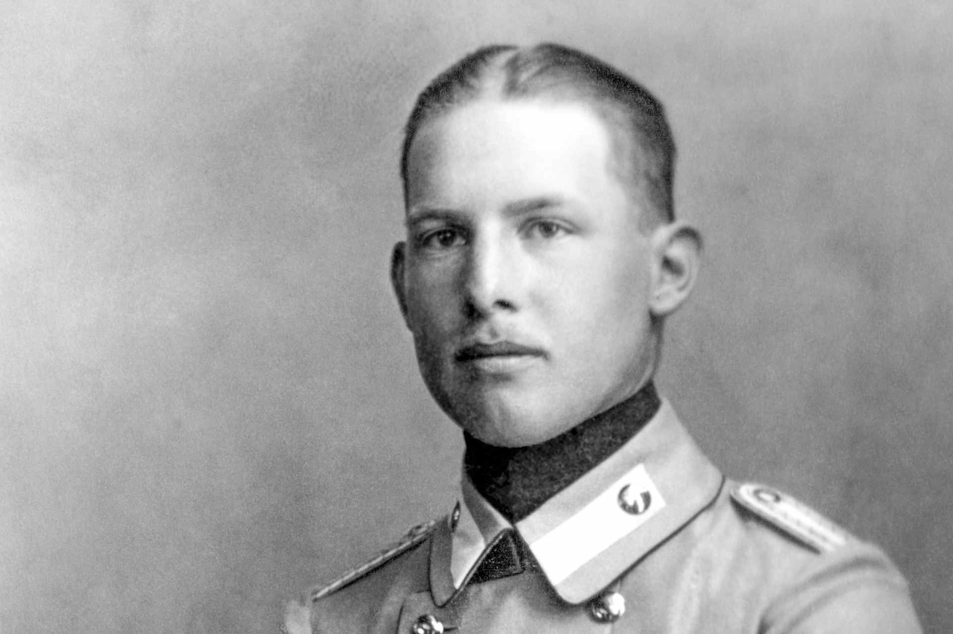 Black and white formal portrait of King Alexander I of Greece, a young man wearing a military uniform, with his short cropped hair parted in the center