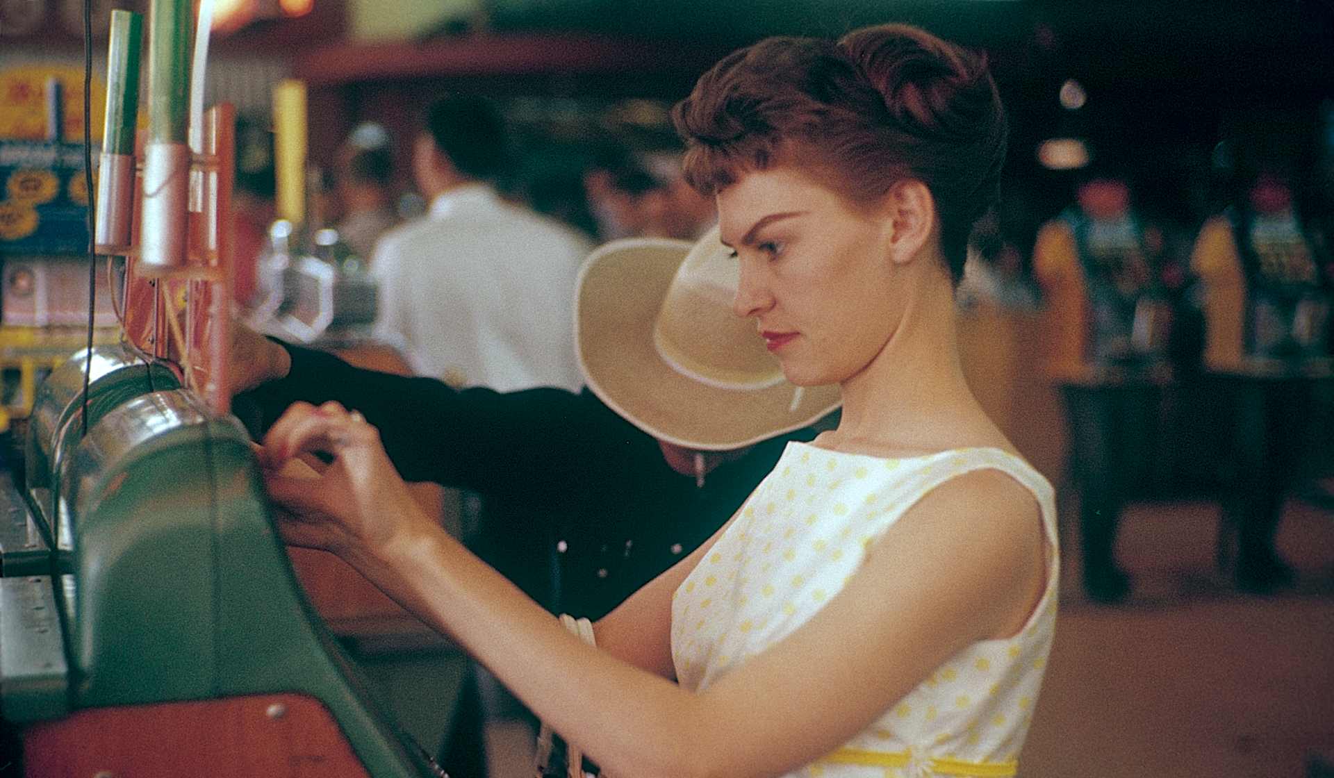 Las Vegas 1959. Young woman at a slot machine. A machine where you put in a coin and pull a lever that...