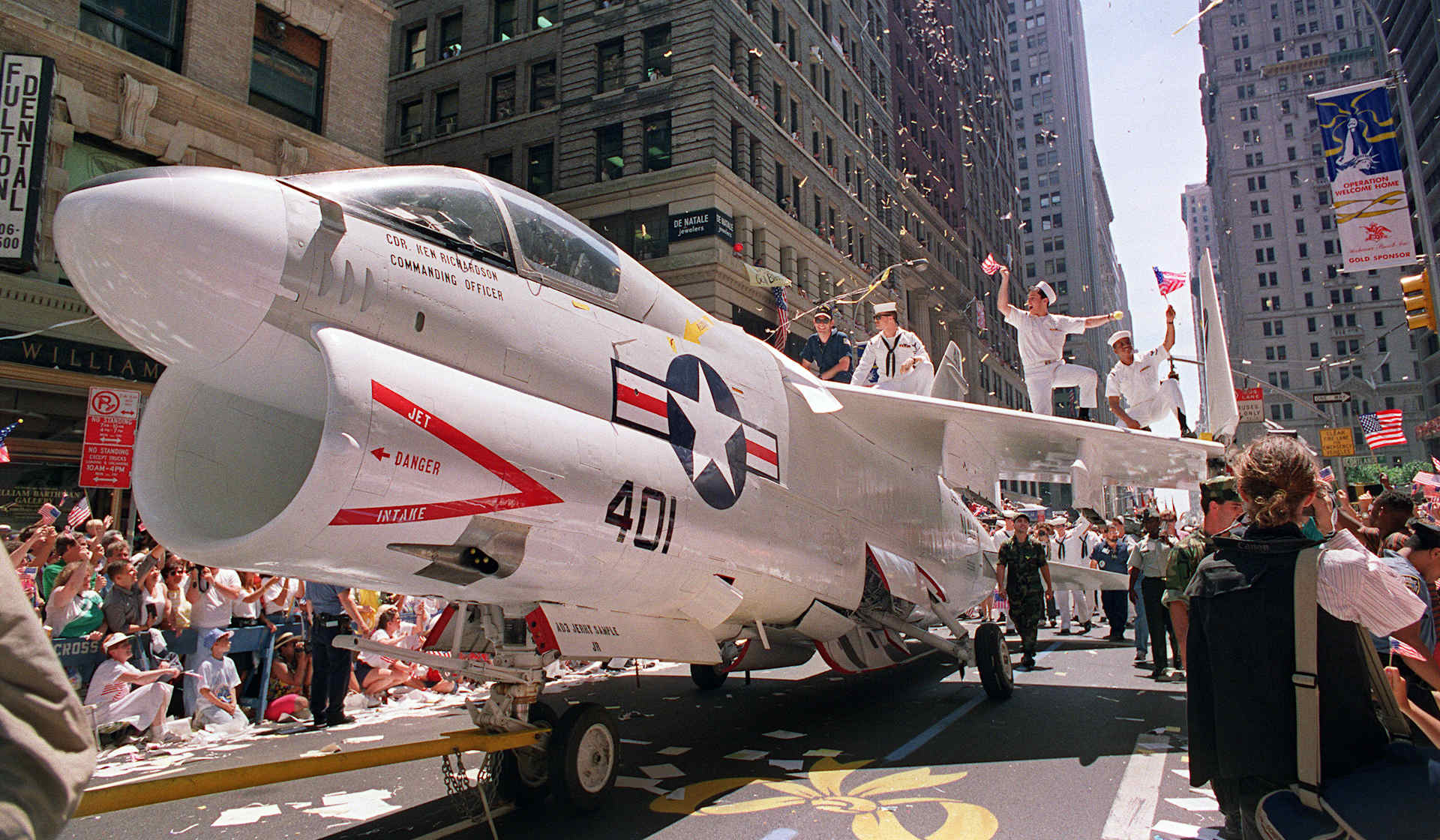 A Navy A-7 Corsair jet is pulled down Broadway in NYC as sailors rejoice on the wings during the Operation Welcome Home ticker tape  parade during the 10 June 1991 celebration for returning Gulf War troops.