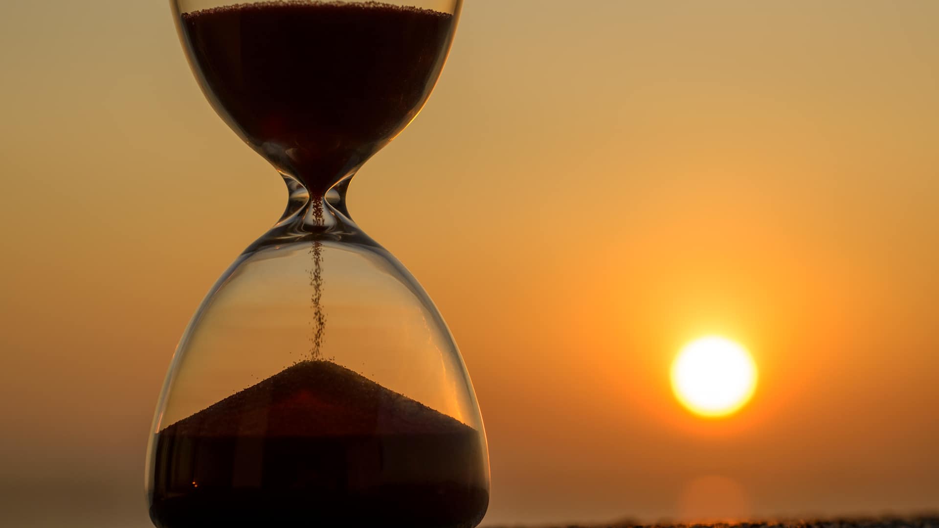 Close-Up Of Hourglass Against Sky During Sunrise