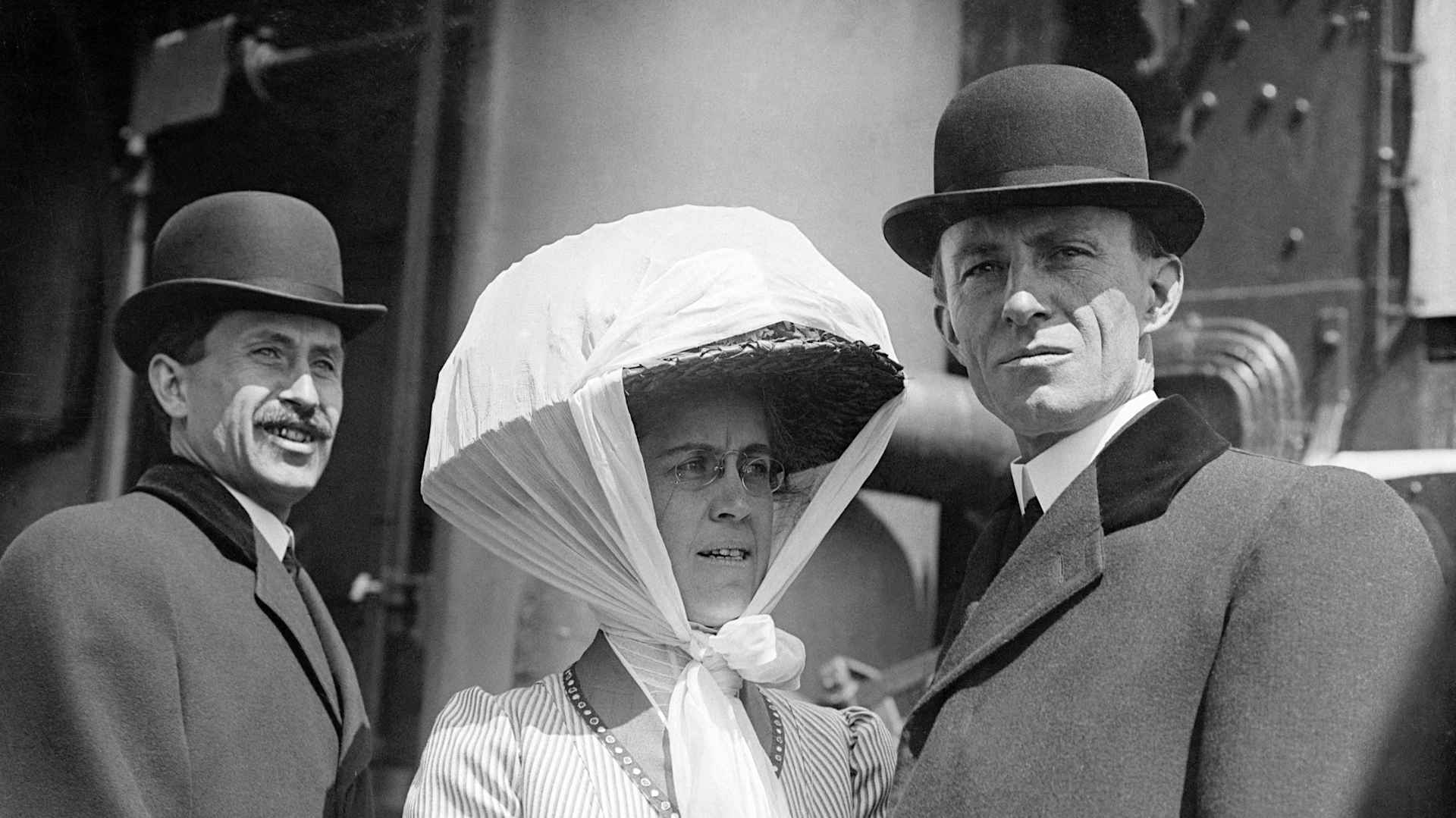 Orville (L) and Wilbur Wright (R) stand with their sister, Katharine, on the deck of a ship.