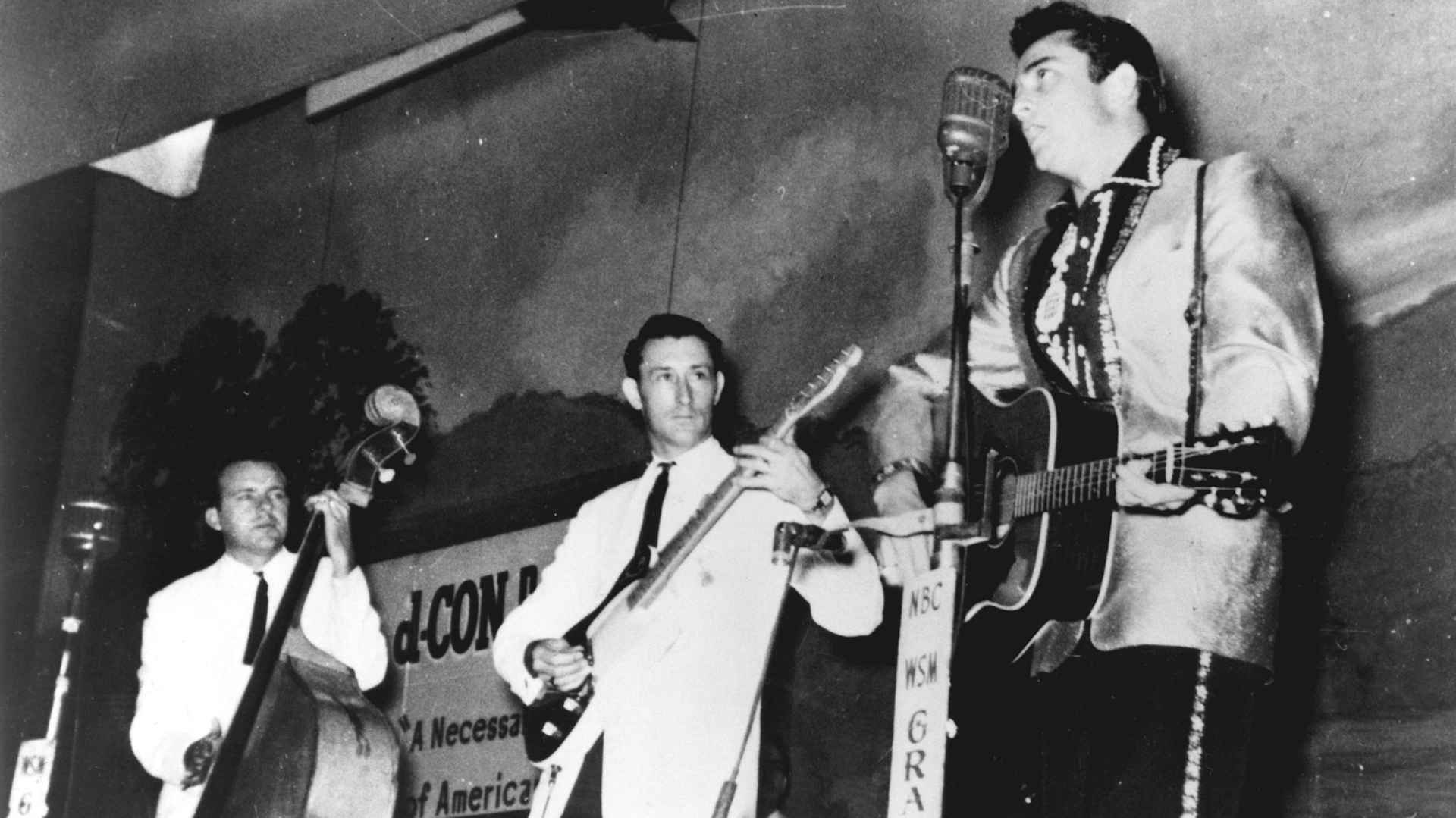 Country singer Johnny Cash performs on the Grand Ole Opry show with his band the Tennessee Two, which included bassist Marshall Grant and guitarist Luther Perkins, 1956.
