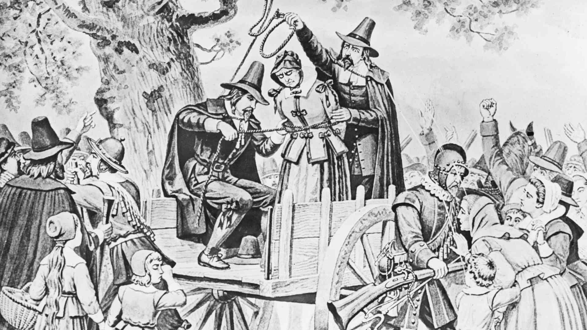 Black and white print of an older colonial-era Salem woman standing on a wooden cart, having a noose put around her neck. Bridget Bishop was the first person executed as part of the Salem witch trials.