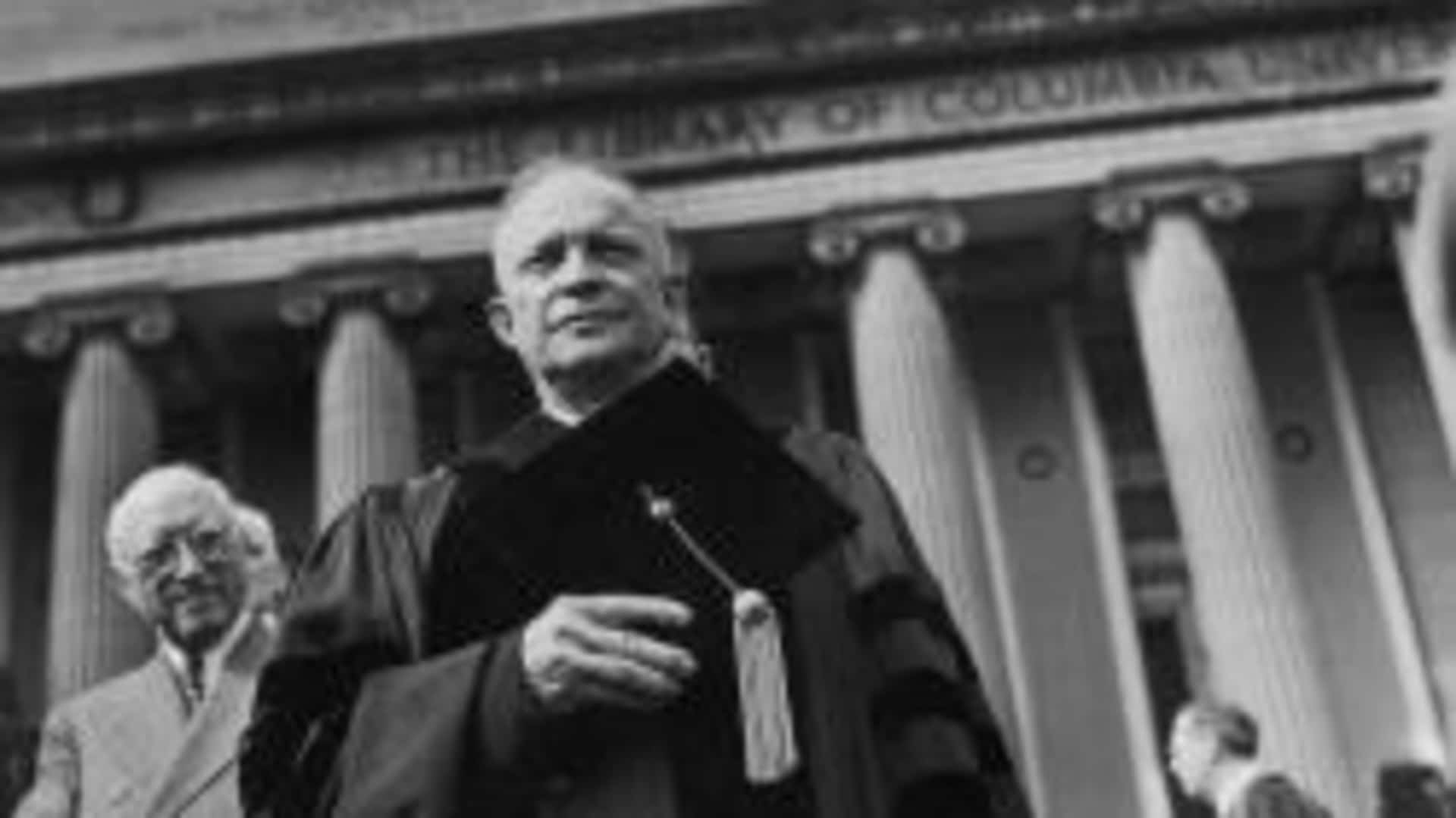 Eisenhower in an academic robe in front of a columned building at Columbia University.