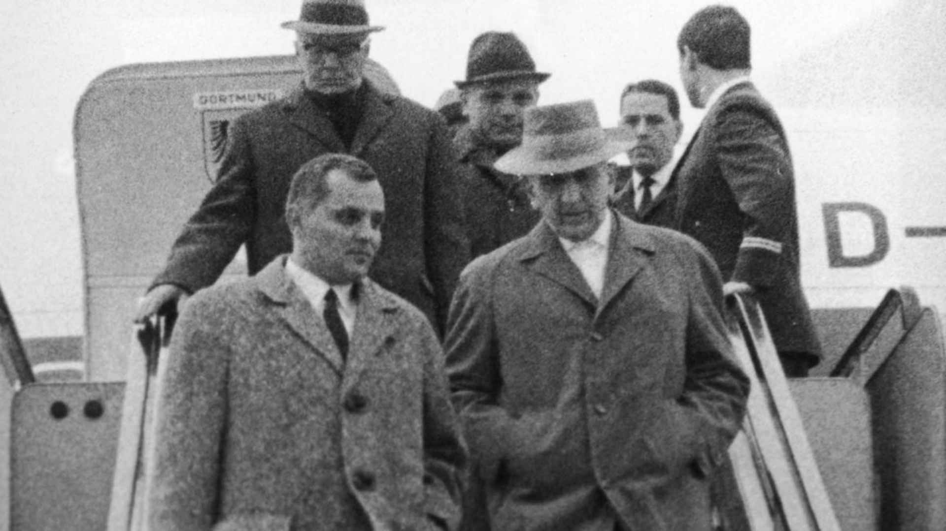 Gerhard Bohne (right) arriving at Frankfurt Airport from Buenos Aires, accompanied by two officials of the district criminal board of Wiesbaden. Bohne would be prosecuted for administering the Nazi's euthanasia program aimed at purifying the Aryan race of people with physical infirmities and mental disabilities.
