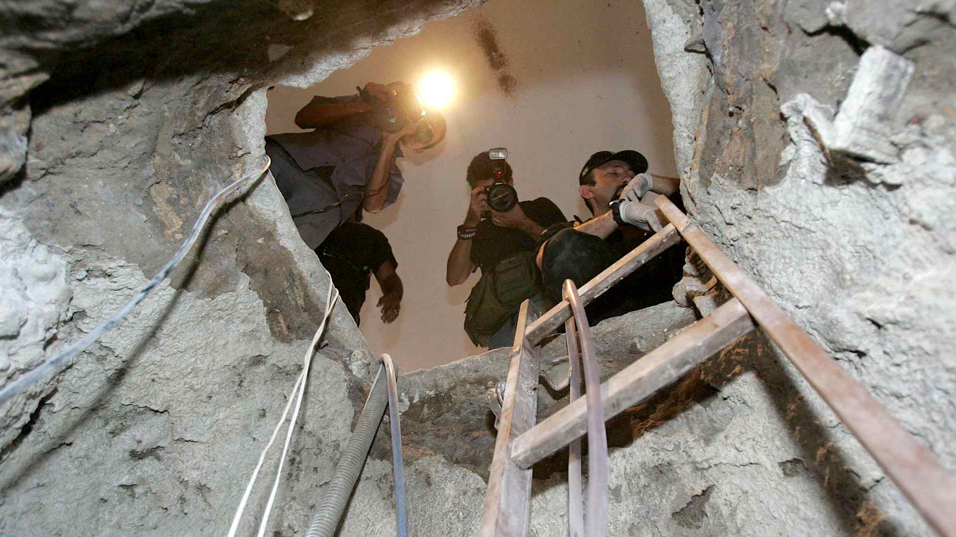 A Brazilian federal police agent, right, and journalists look through the tunnel dug by the Central Bank robbers August 8, 2005, in Fortaleza, northeastern Brazil. Thieves dug a 260-foot-long tunnel into a Brazilian Central Bank branch to steal 65 million dollars, the country's biggest-ever bank heist.