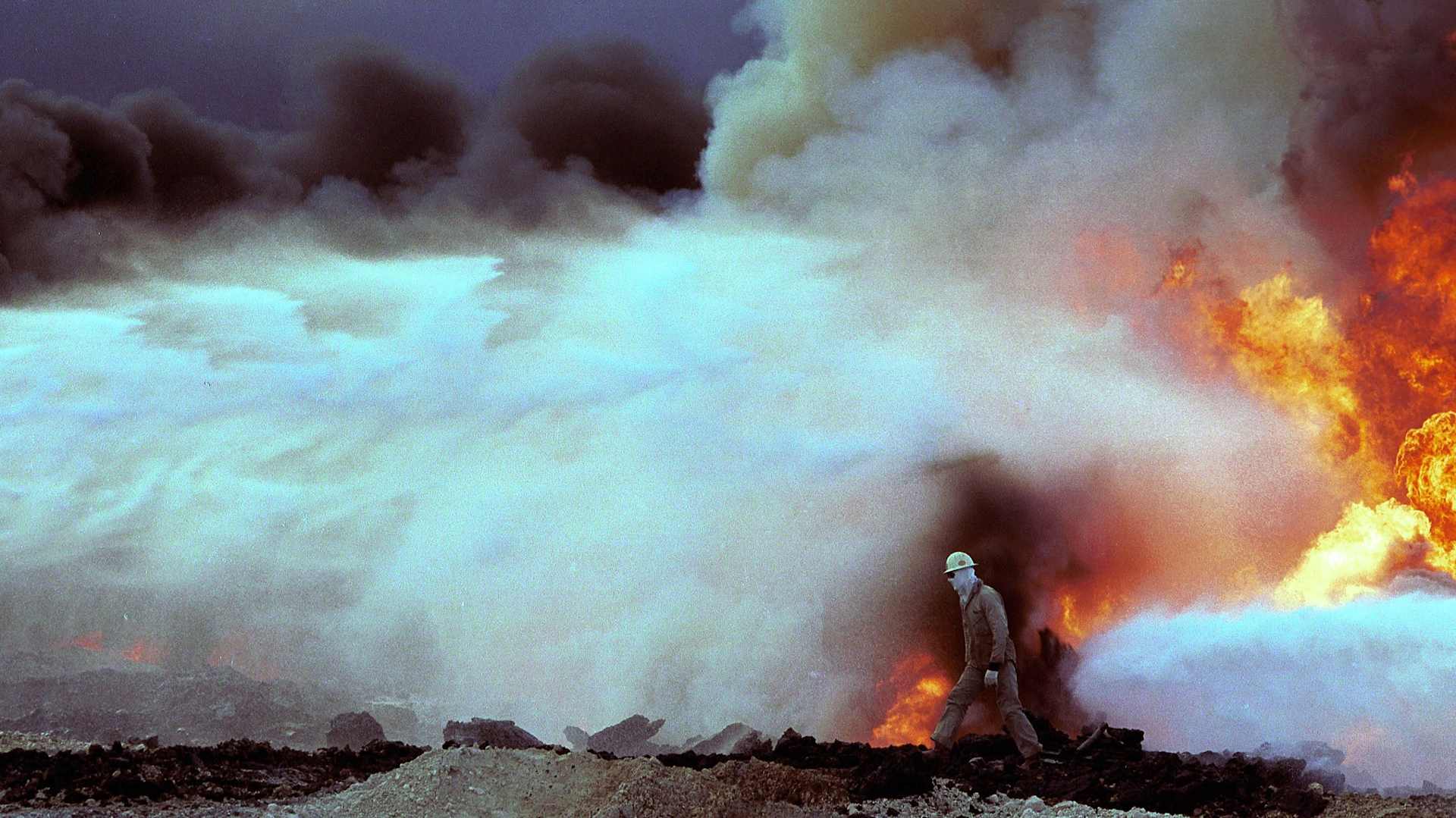 GREATER BURHAN OIL FIELD, KUWAIT - AUGUST 06: (.) An unidentified firefighter walks through an inferno of fire, smoke and water August 6, 1991 at the Greater Burhan oil field in Kuwait. When the Gulf War ended in February 1991 expert teams of specialized firefighters, mainly from the U.S. and Canada, arrived to extinguish the fires and cap the wells. (Photo by Per-Anders Pettersson/Getty Images)
