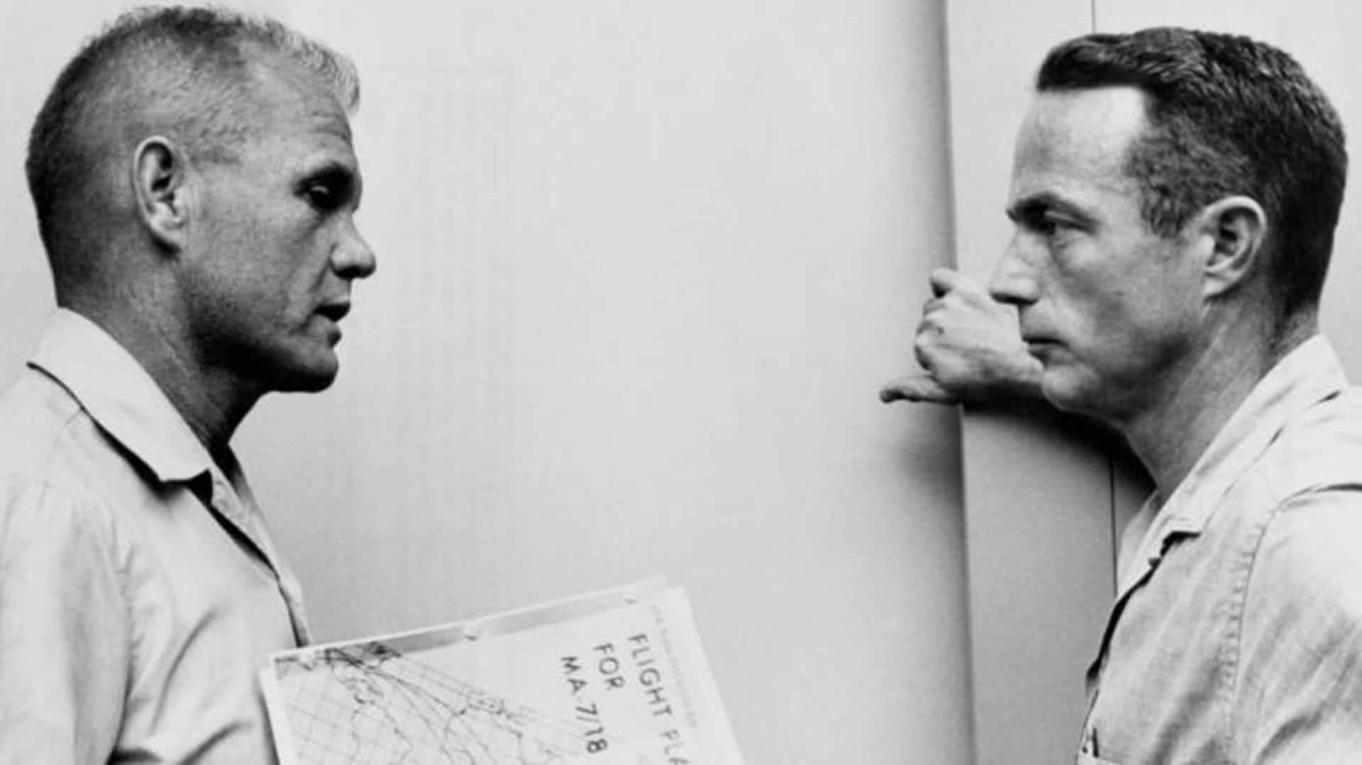 John Glenn and Scott Carpenter reviewing the flight plan for the Mercury-Atlas 7 mission at Cape Canaveral, Florida. (Credit: NASA)