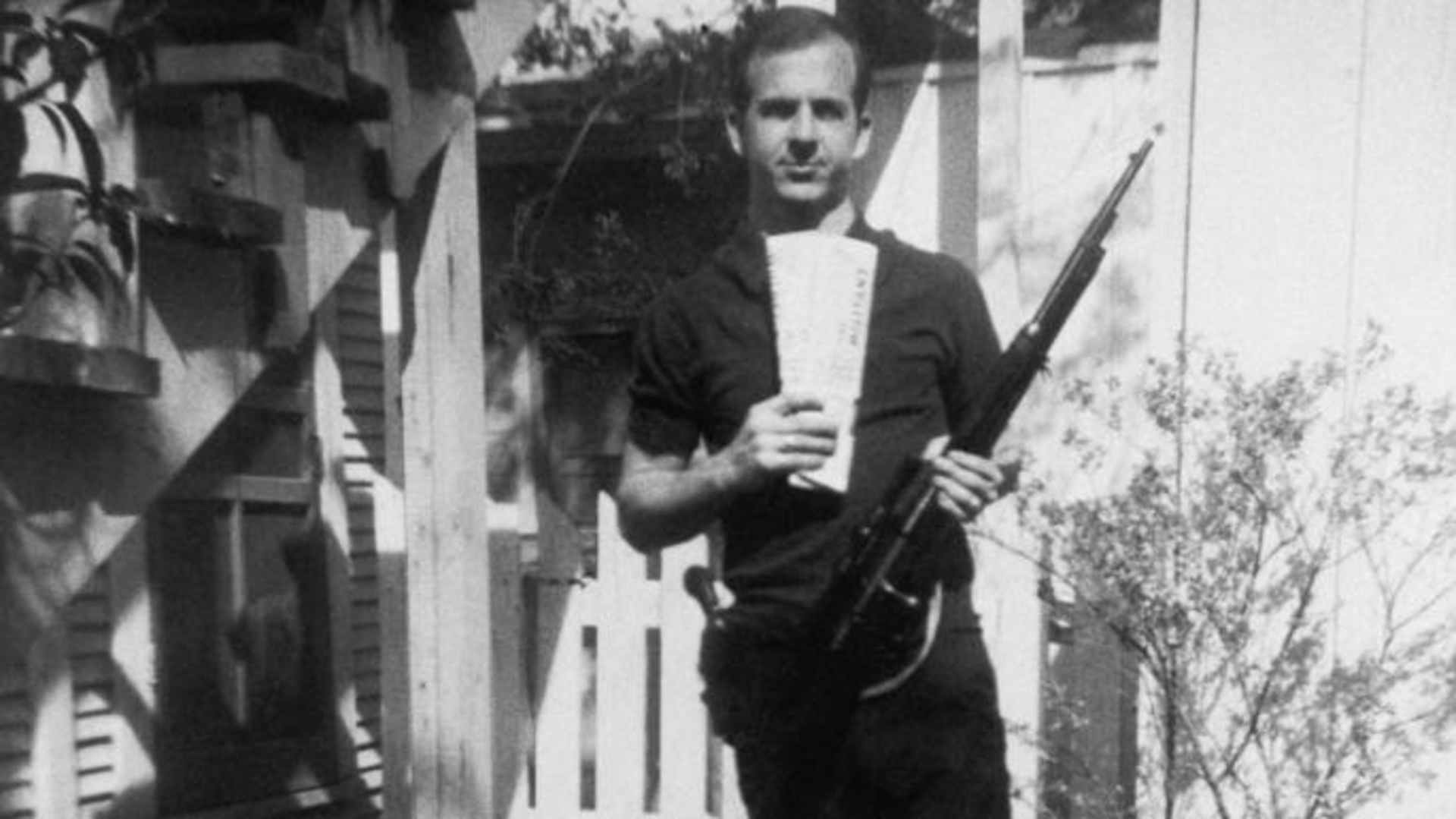 Lee Harvey Oswald holds a Mannlicher-Carcano rifle and newspapers in a backyard. This is one of the controversial photos used in the investigation of the assassination of John F. Kennedy in 1963. (Credit: Corbis via Getty Images)