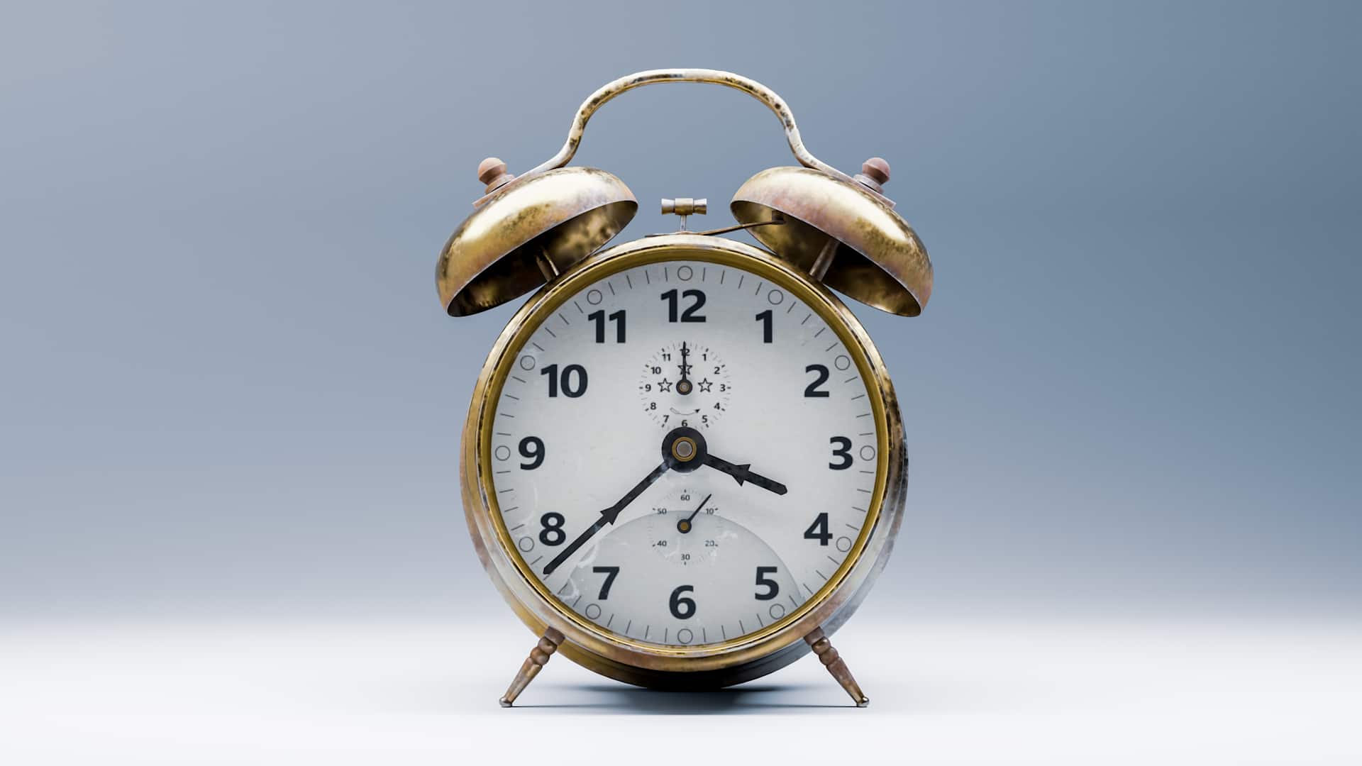 Gold colored metal mechanical vintage alarm clock on grey shaded background.