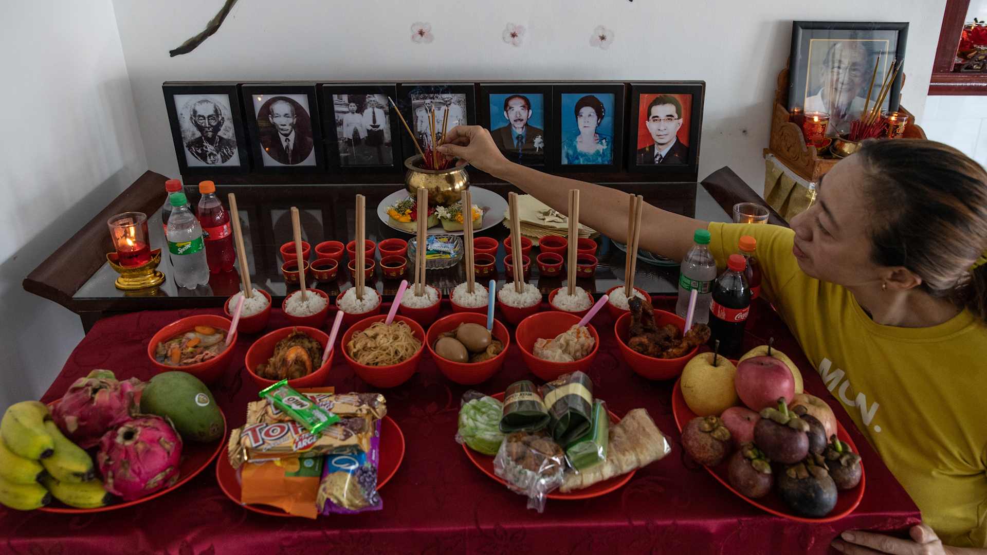 An Indonesian Taoist devotee burns incense sticks and lays out food offerings for ancestors during the Hungry Ghost celebration. Food offerings are made while paper money and incense sticks are burnt outside homes to keep the spirits of dead ancestors happy and bring fortune and prosperity.