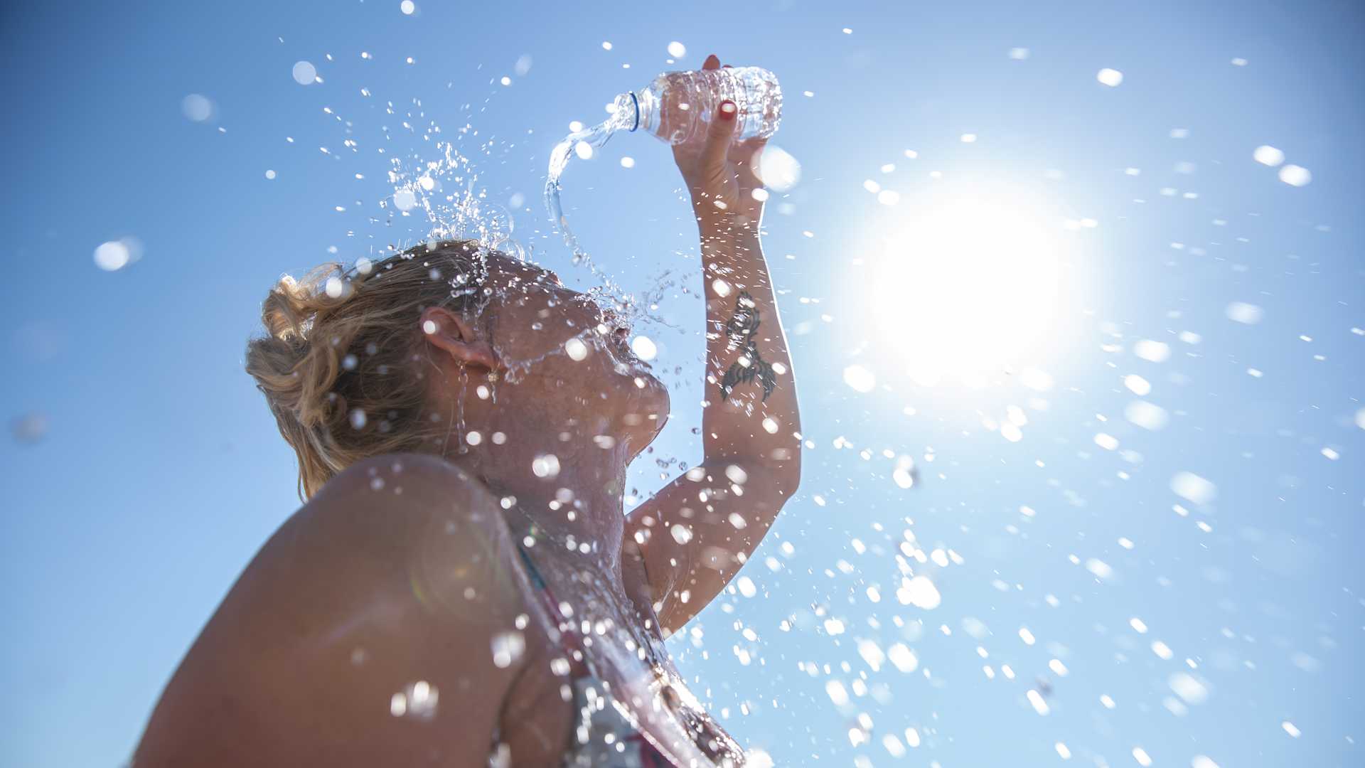 A young woman cools down with cold water during the summer heat.