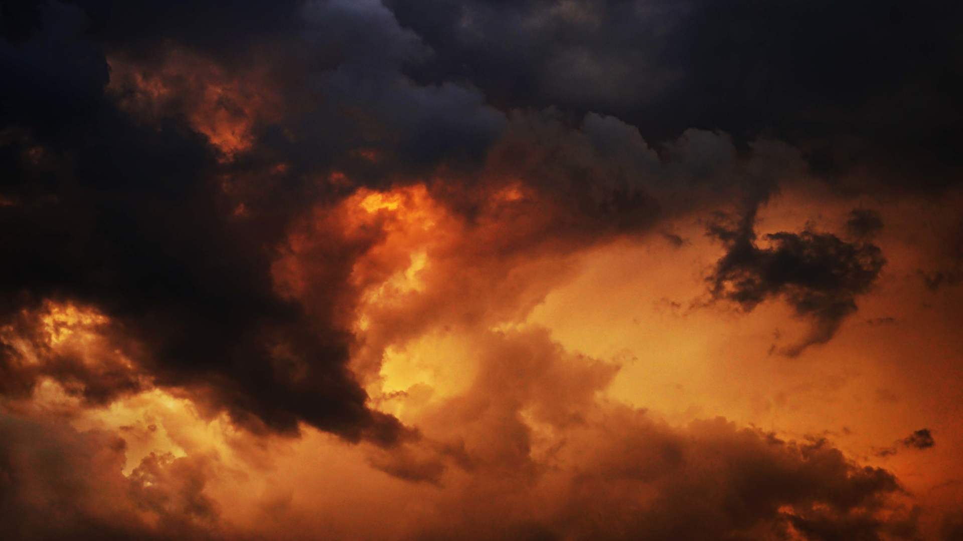 Yellow orange red blue black sky with clouds. Dark dramatic  background. Fire, glow. Storm, lightning. Or war, horror concept.