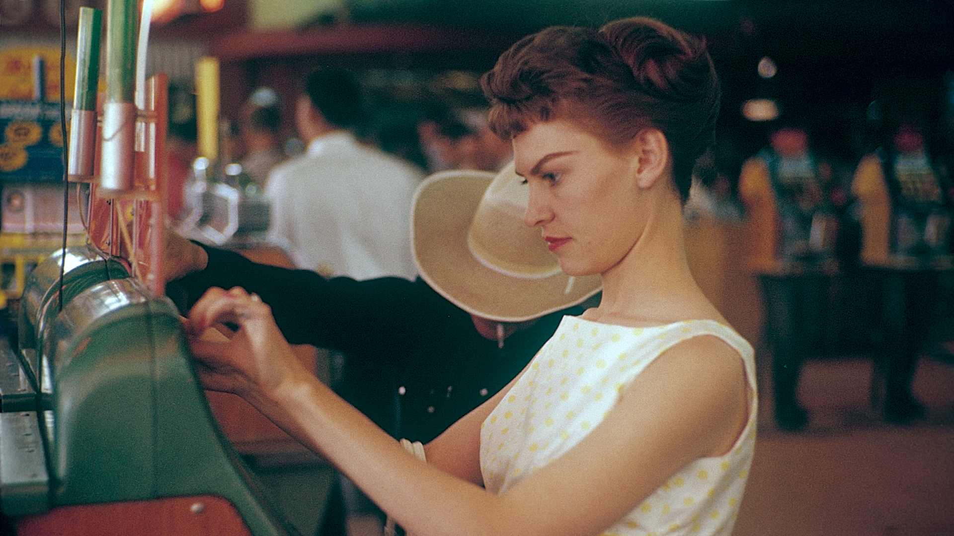 Las Vegas 1959. Young woman at a slot machine. A machine where you put in a coin and pull a lever that...