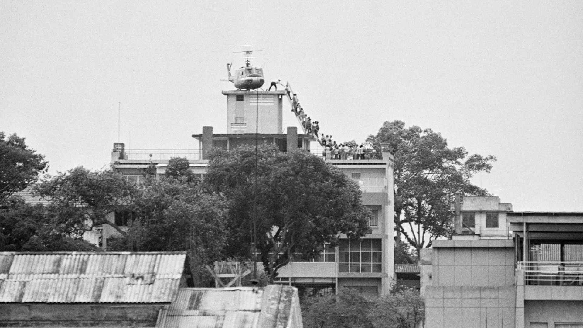 April 29, 1975: A CIA employee helps Vietnamese evacuees onto an Air America helicopter from the rooftop of 22 Gia Long Street, a half mile from the U.S. Embassy.