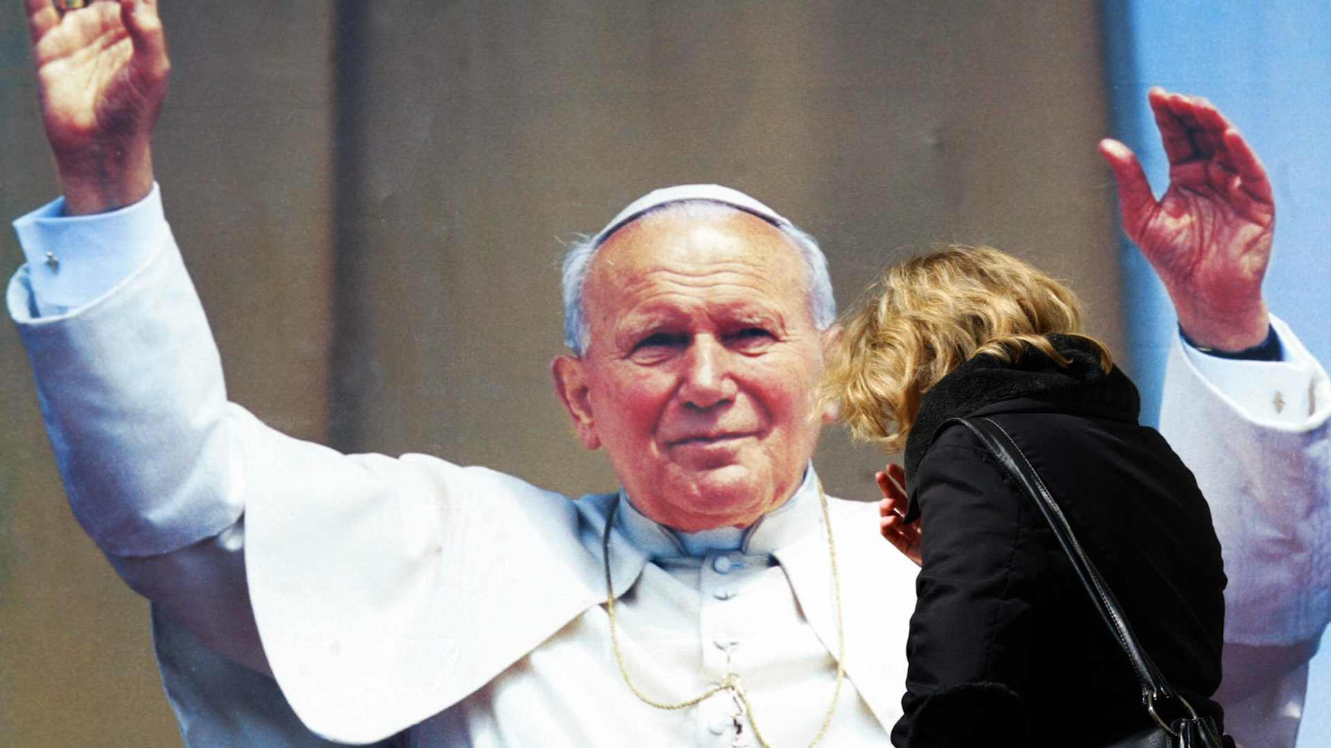 A Catholic prays in front of portrait of