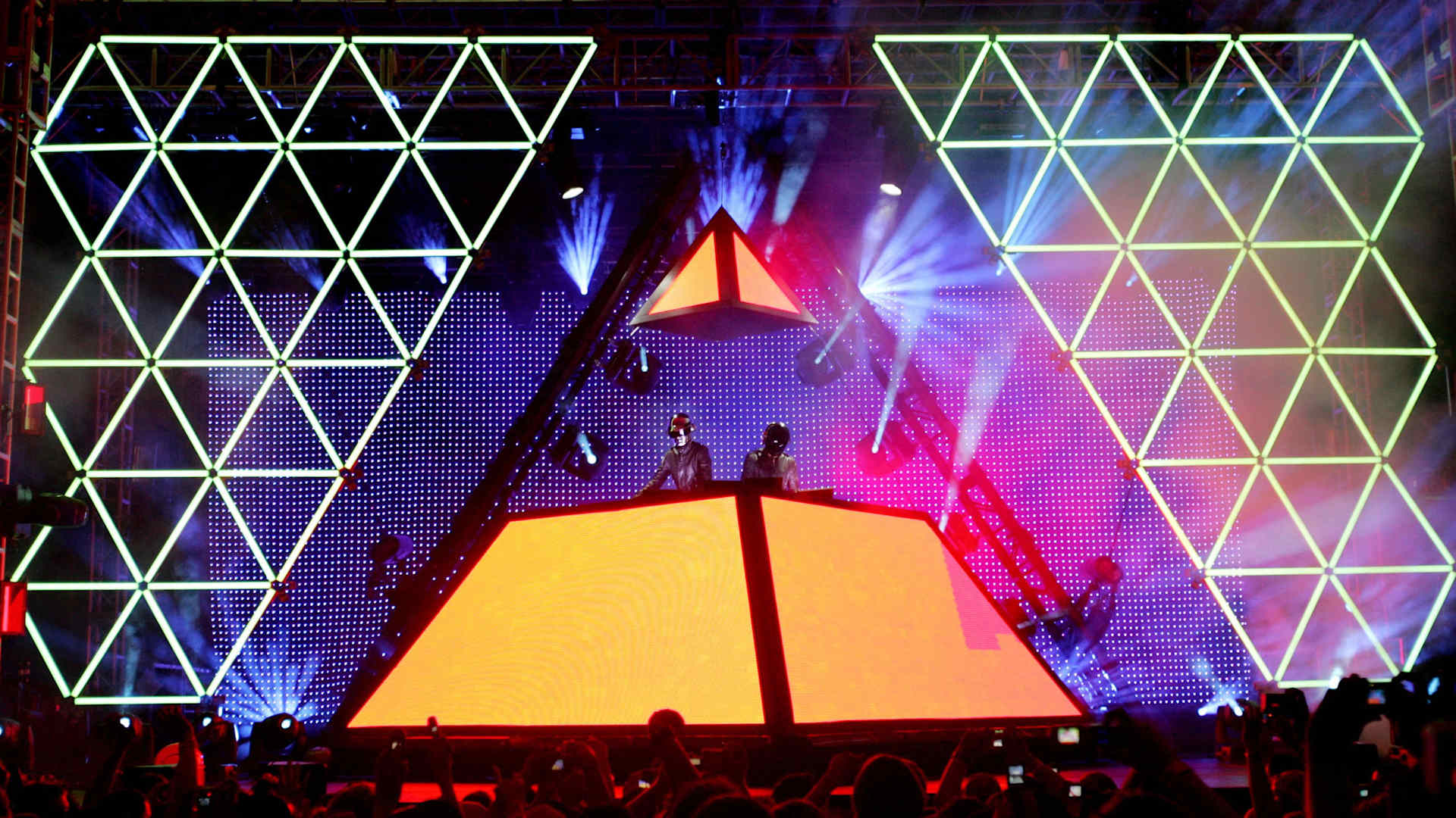 Daft Punk musicians in space suit-looking costumes perform from an elaborate colored-light pyramid above the 2006 Coachella Music Festival stage