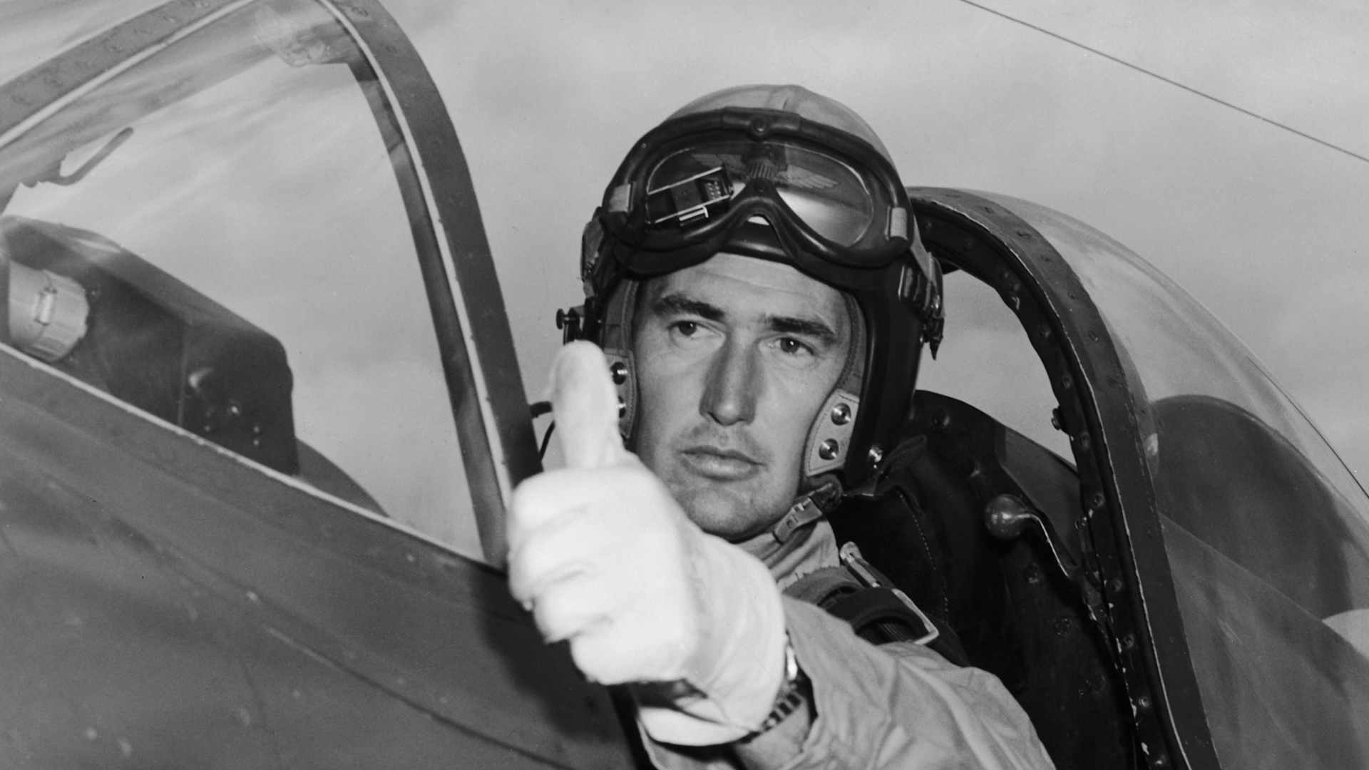 Professional baseball player Ted Williams in the open cockpit of a Korean War fighter plane, giving the thumbs up.