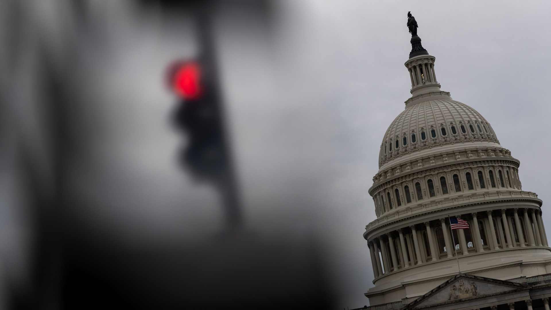 Security fencing and a red stop light in front of the U.S. Capitol building in Washington, DC.