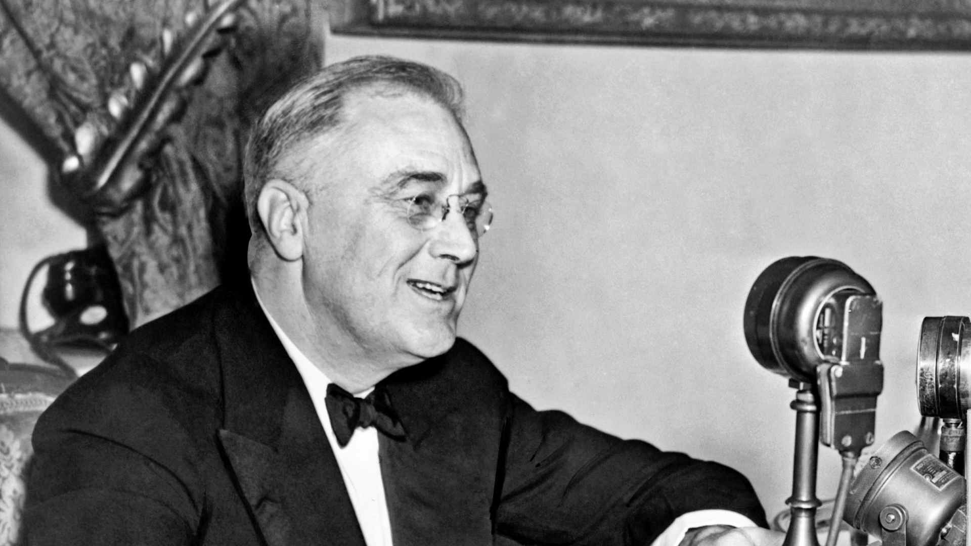 Franklin D. Roosevelt seated behind a microphone