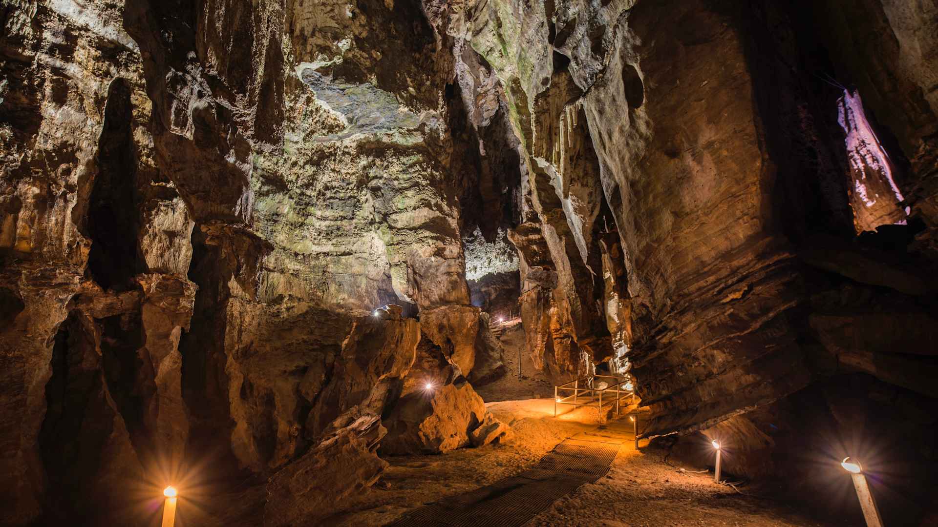 entryway to a tall dark cave, with lights