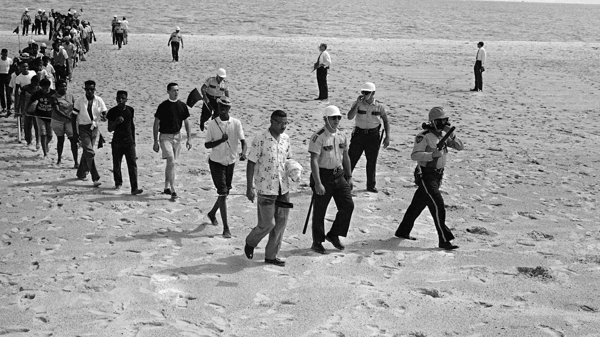 In this June 23, 1963, file photo, Black and white demonstrators, under arrest, walk off the beach at Biloxi, Miss., after staging a wade-in to try to desegregate the Gulf Coast beach