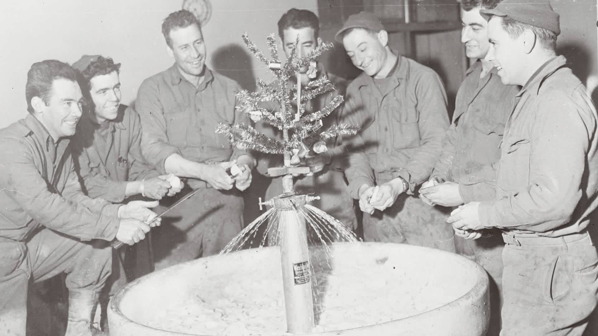 American soldiers of 101st infantry regiment peel potatoes around a sink decorated with a tiny Christmas tree.