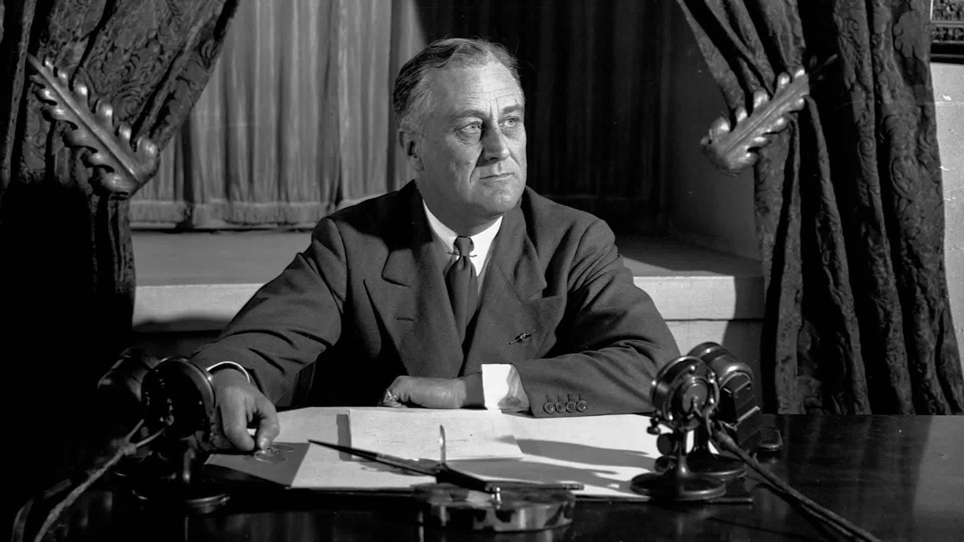 Franklin Roosevelt sitting at his desk, looking pensively to the side