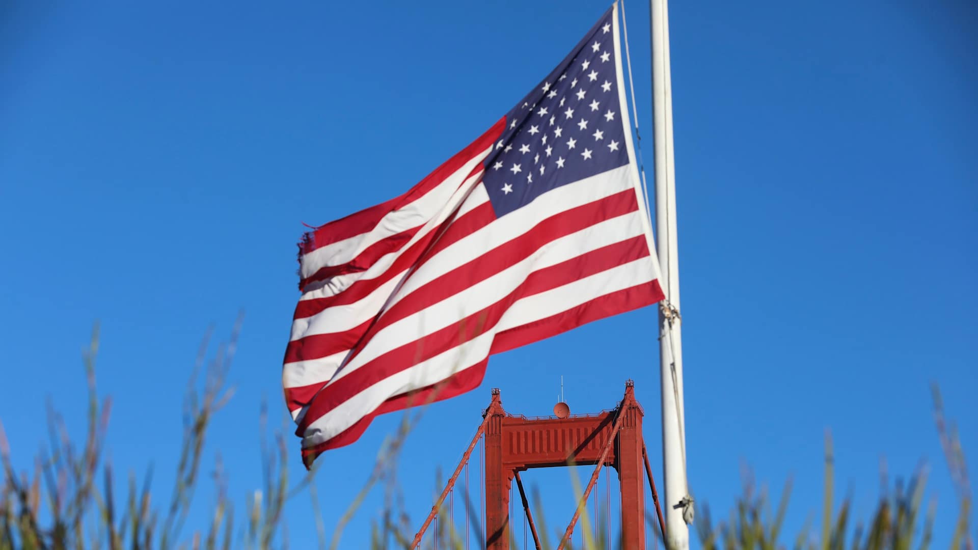 An American flag near the Golden Gate Bridge in San Francisco, California, US, on Monday, Jan. 23, 2023. A $400 million federal grant to upgrade and retrofit the Golden Gate Bridge to ensure it can withstand the impacts of a major earthquake was unveiled following the passage of the bipartisan infrastructure law in Congress last year that included funding to repair and rebuild bridges across the country. Photographer: Benjamin Fanjoy/Bloomberg via Getty Images