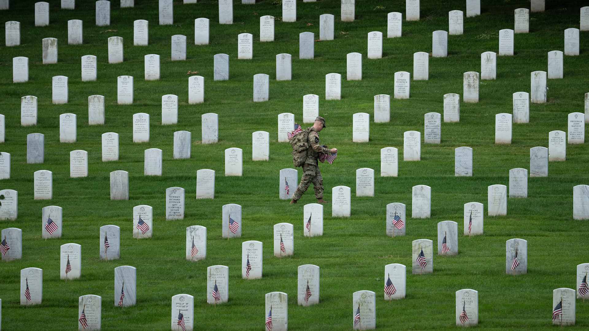 ARLINGTON, VA - MAY 26: A member of the 3rd U.S. Infantry Regiment places flags at the headstones of U.S. military personnel buried at Arlington National Cemetery, in preparation for Memorial Day, on May 26, 2022 in Arlington, Virginia. Nearly 1000 service members entered the cemetery at pre-dawn hours to begin the process of placing a flag in front of more than 260,000 headstones. (Photo by Drew Angerer/Getty Images)
