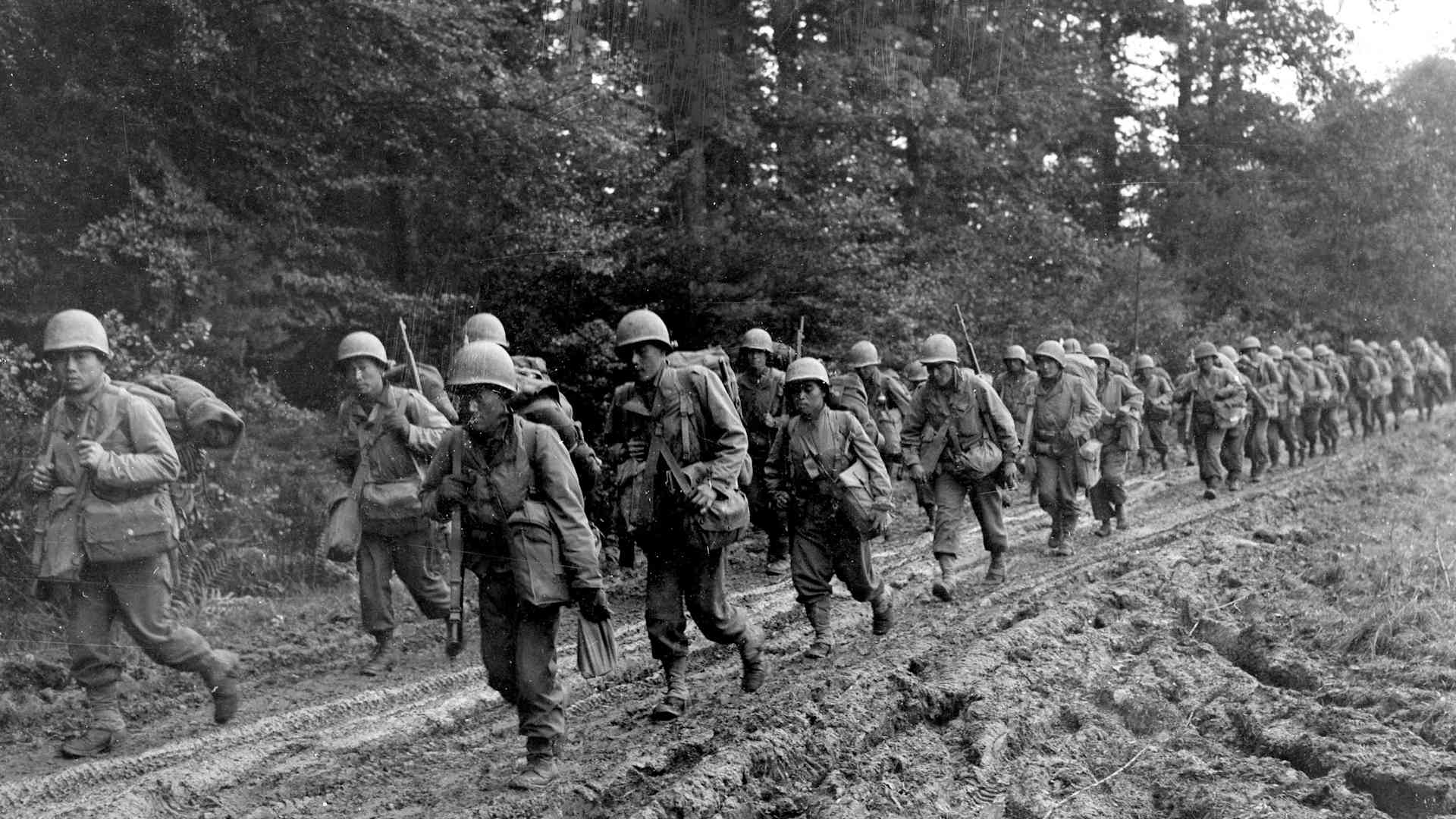 Japanese-American infantrymen of the 442nd Combat Team hike up a muddy French road to their new bivouac area, October 14, 1944.