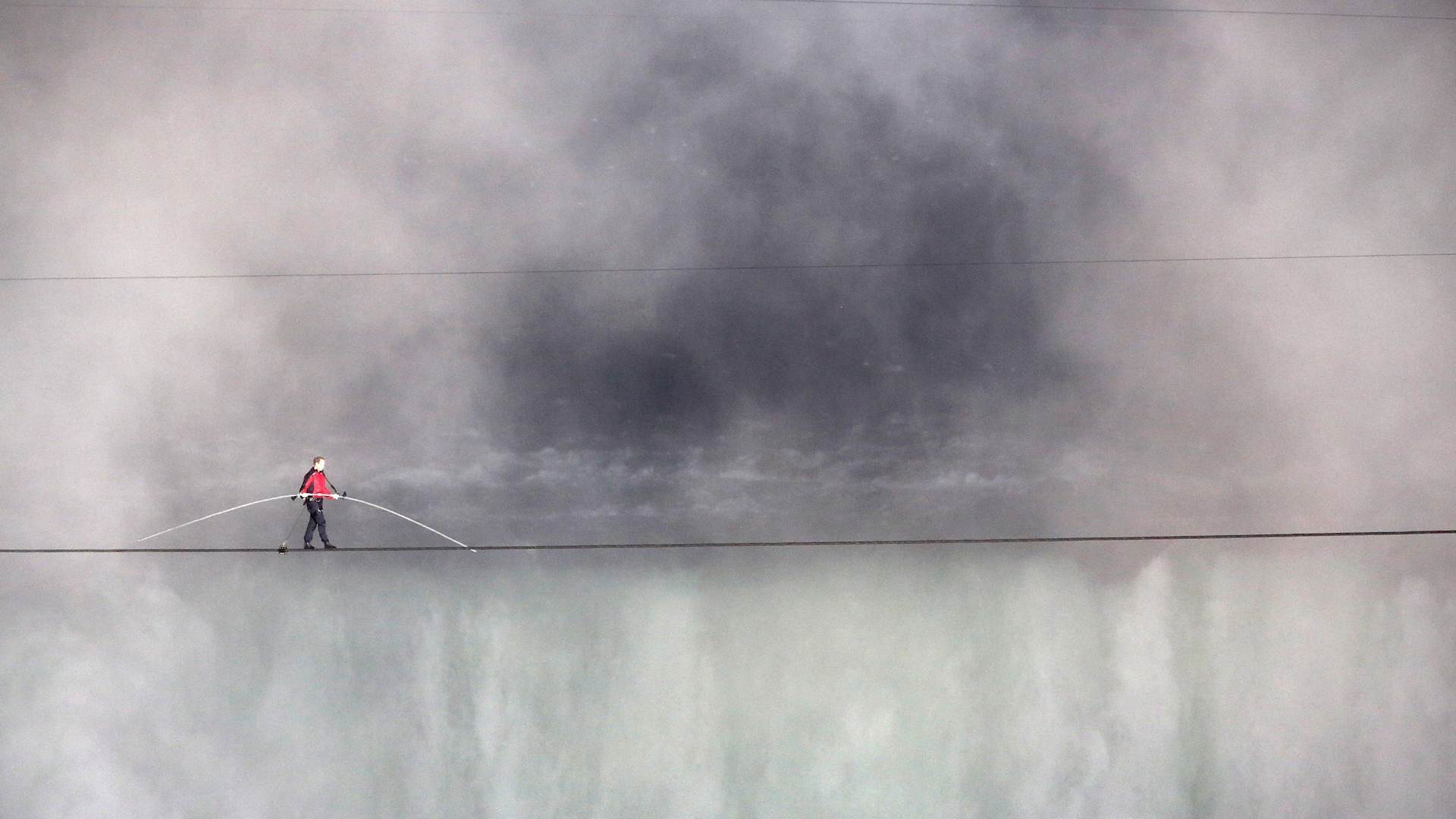 NIAGARA FALLS, CANADA - JUNE 15: Aerialist Nik Wallenda tighropes over the Niagara Falls June 15, 2012 in Niagara Falls, Canada. Wallenda walked across the 1,800 foot long, 2 inch-wide wire Friday night as the first person to cross directly over the falls from the U.S. into Canada. Wallenda, 33 and a father of three, is a seventh generation member of the famed Flying Wallendas who trace their roots to 1780 Austria-Hungary, when ancestors traveled as a band of acrobats, aerialists, jugglers, animal trainers and trapeze artists. ABC televised the event and insisted the daredevil wear a teathered harness to prevent live coverage of a potentially deadly fall 190 feet into the churning torrent below. (Photo by John Moore/Getty Images)