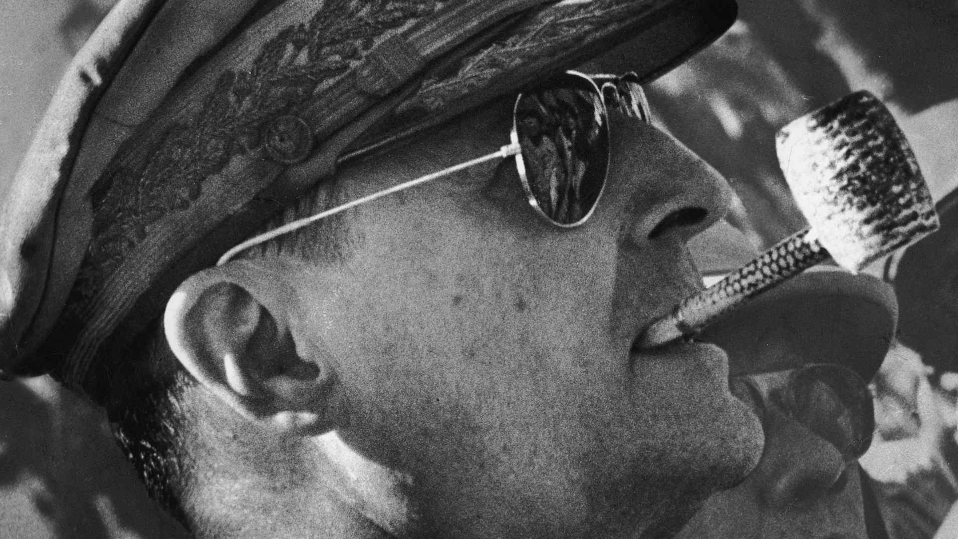 Headshot of American military leader General Douglas MacArthur (1880 - 1964), wearing a military uniform and sunglasses, smoking a corn cob pipe, Leyte Island, Philippines.