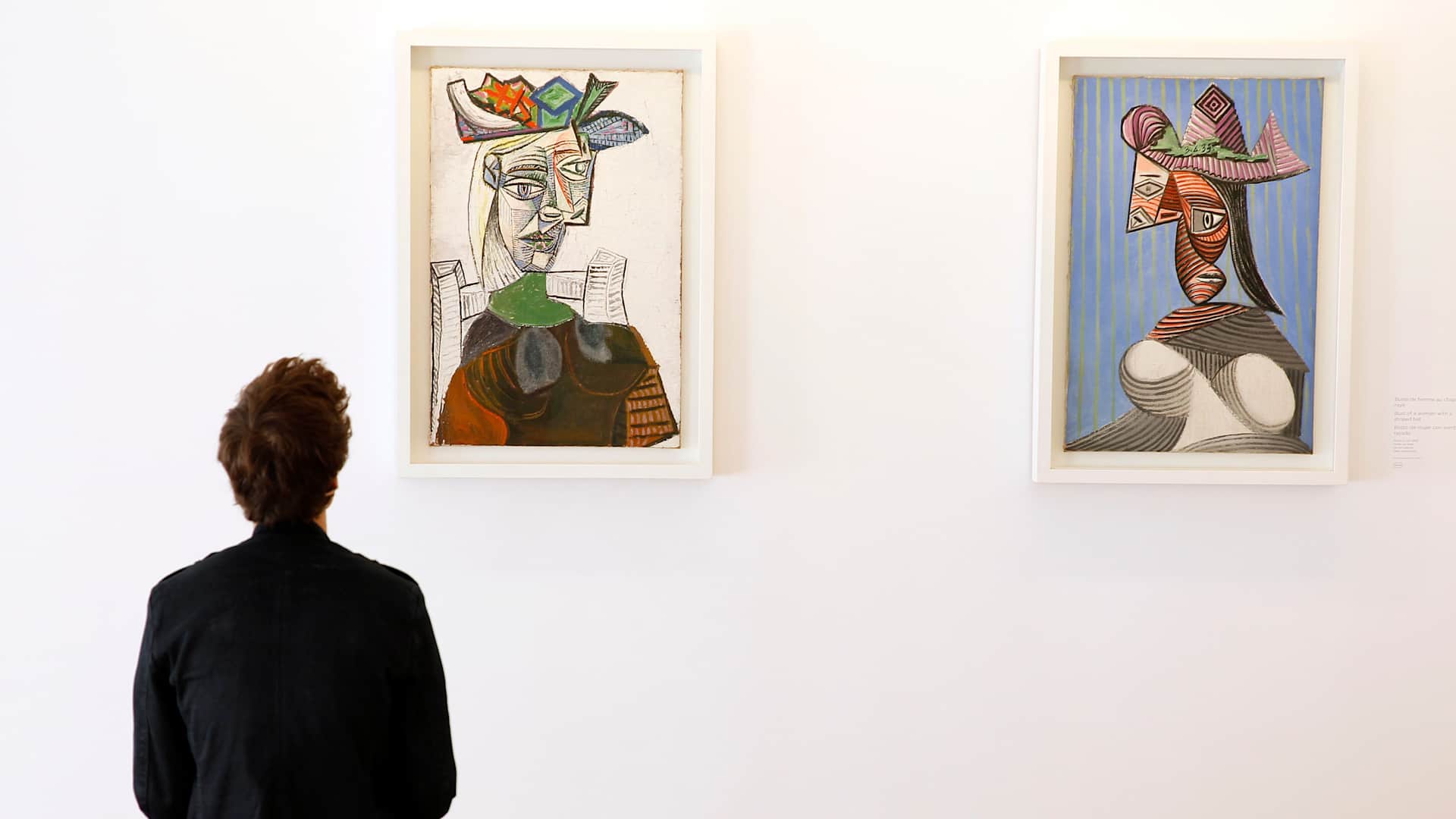 PARIS, FRANCE - OCTOBER 18: A visitor looks at Picasso paintings 'Seated woman with a hat' and 'Bust of a woman with a striped' during the press day at the Picasso Museum, on October 18, 2014 in Paris, France. The museum will reopen on the 25th and will be inaugurated the same day by French president Francois Hollande. (Photo by Thierry Chesnot/Getty Images)