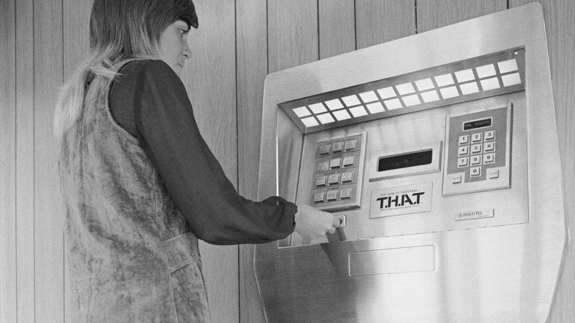 Jaynee Hurd demonstrates the first automated teller machine at the Los Angeles branch of the Bank of California. Named "THAT", which stands for twenty-four hour automatic teller, the machine can perform ninety-five percent of the functions of a teller when operated by the bank's clients.