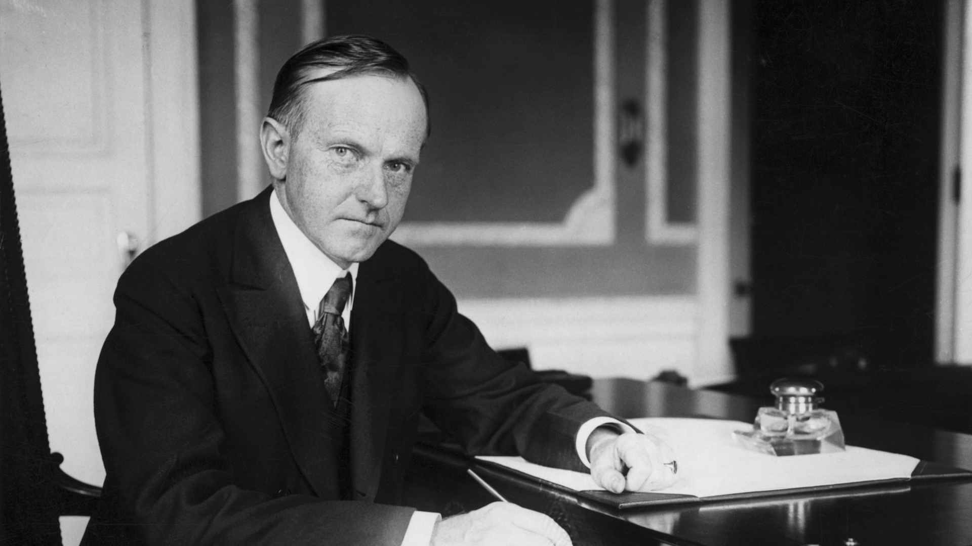 Calvin Coolidge (1872-1933), 30th President, sitting at his desk.