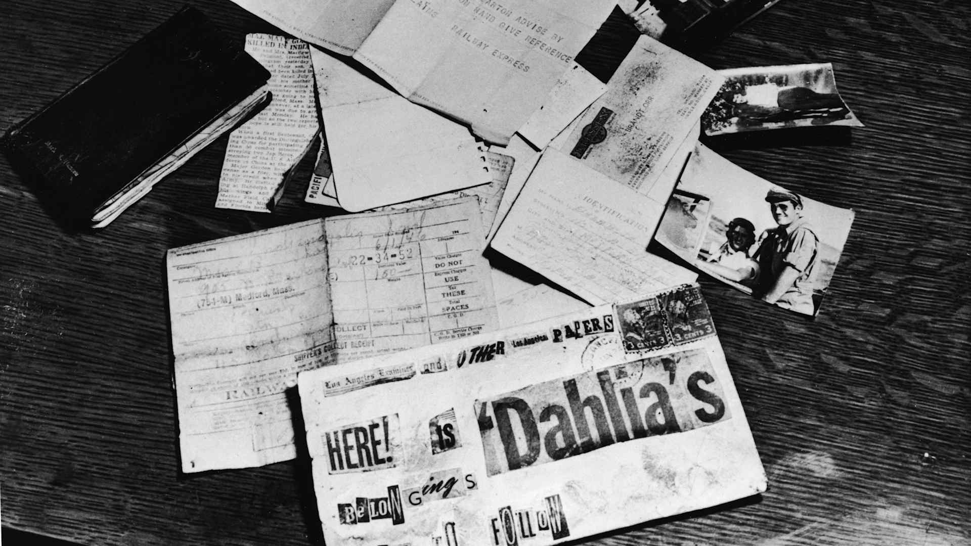 Evidence concerning the murder of American aspiring actress and murder victim Elizabeth Short (1924 - 1947), known as the 'Black Dahlia,' is strown across a table at the Los Angeles District Attorney's office, Los Angeles, California, 1947. On the table is a black address book, a newspaper clipping about the death of Short's supposed fiance and American Amy Major Matthew M. Gordon Jr., Short's birth certificate, a business card, a threatening letter assembled from newspaper lettering, a baggage check from a Greyhound bus depot, a Western Union telegram, and several photographs of Short. (Photo by INTERNATIONAL NEWS PHOTO/Getty Images)
