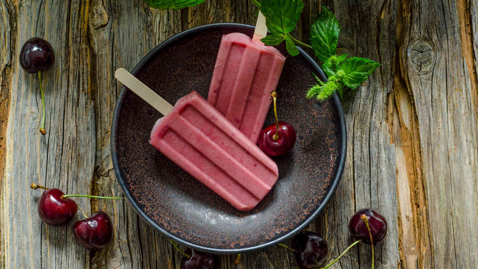 Two cherry popsicles in a bowl.